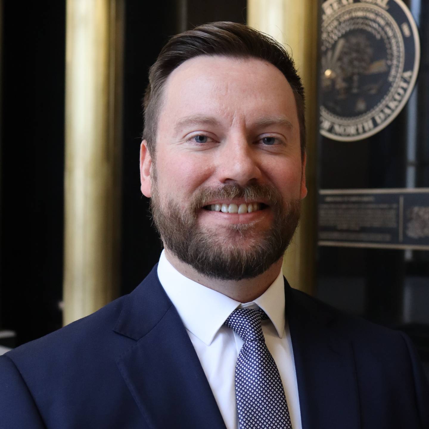 A man with a beard wearing a suit smiling.