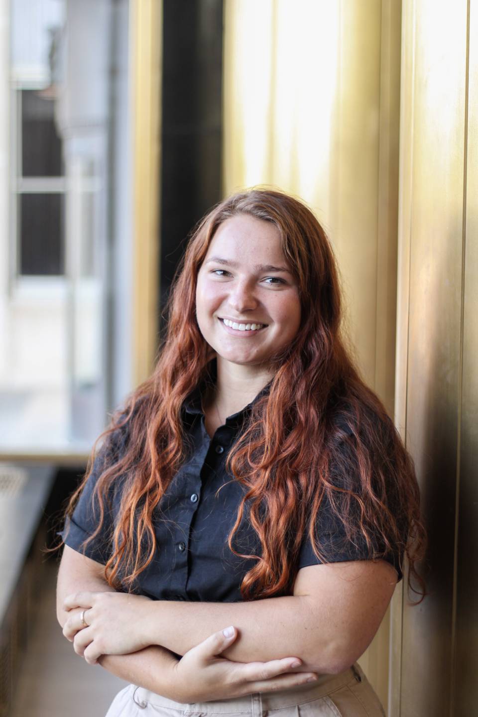 A woman with red hair wearing a black shirt, smiling.