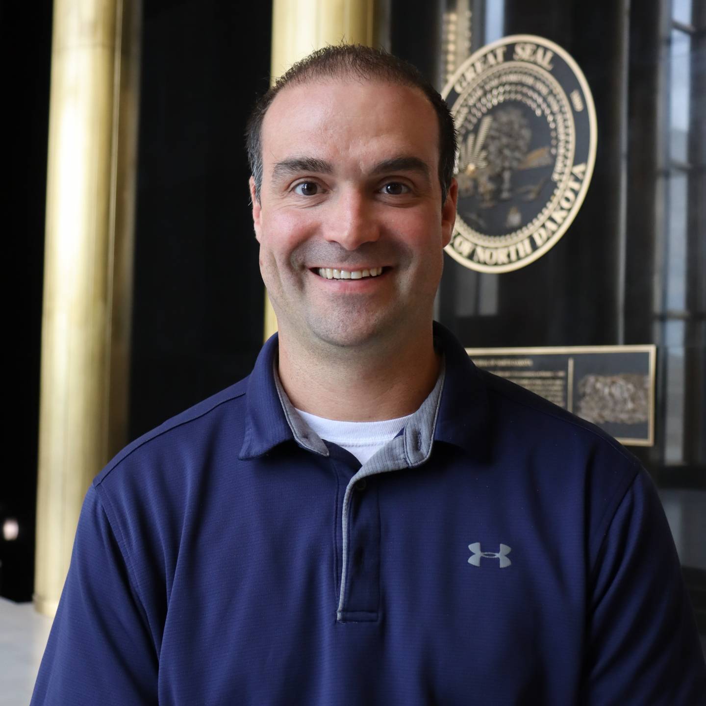 A man in a blue polo smiling.