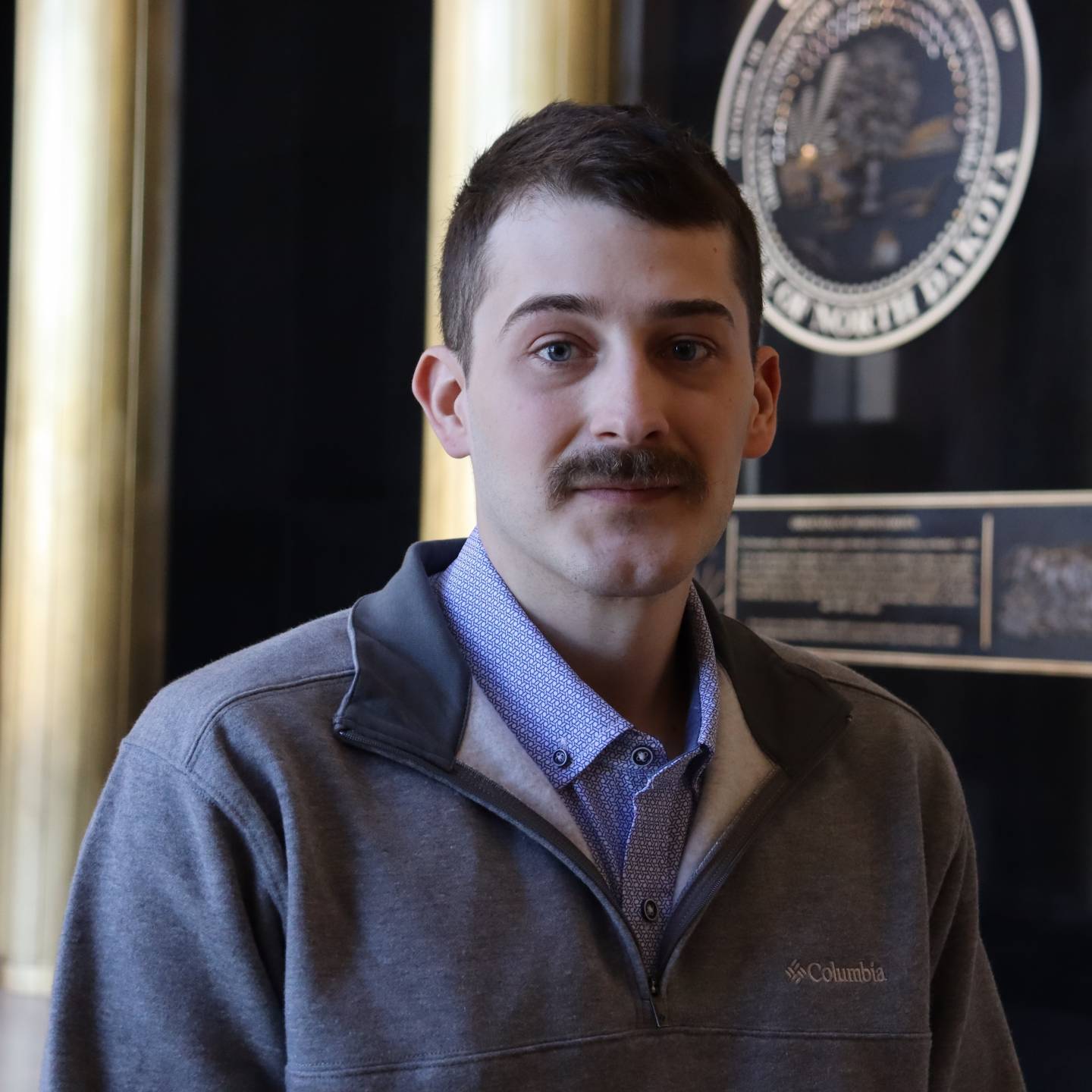 A man with a moustache looking forward.